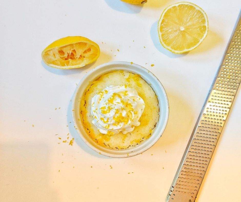 Lemon mug cake with whipped cream, lemon zest, and lemon halves