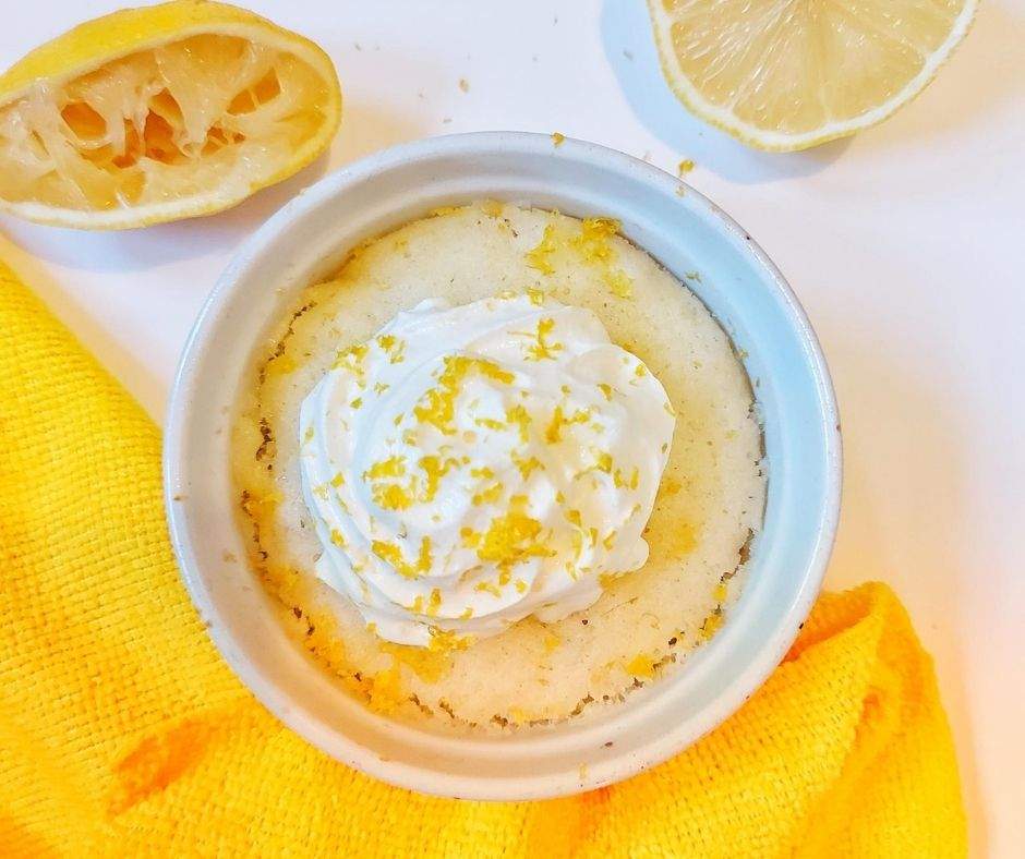 Lemon mug cake that tastes like sunshine (lemon cake with whipped cream, lemon zest, and lemon halves)