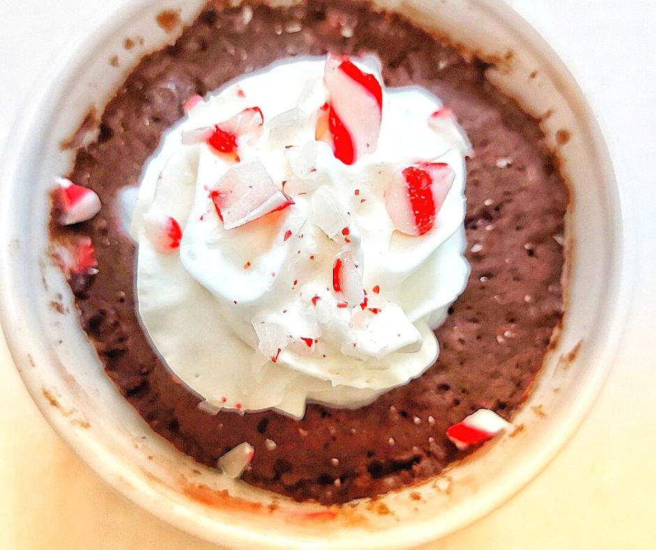 Christmas mug cake topped with whipped cream and crushed candy canes