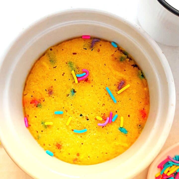 Sugar cookie mug cake on a fork with a glass of milk and sprinkles