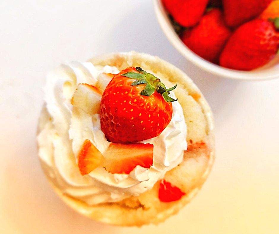 Strawberry mug cake with whipped cream and strawberries on top