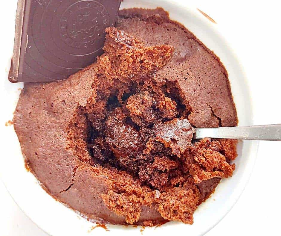 Gooey chocolate mug cake with a square of melted chocolate