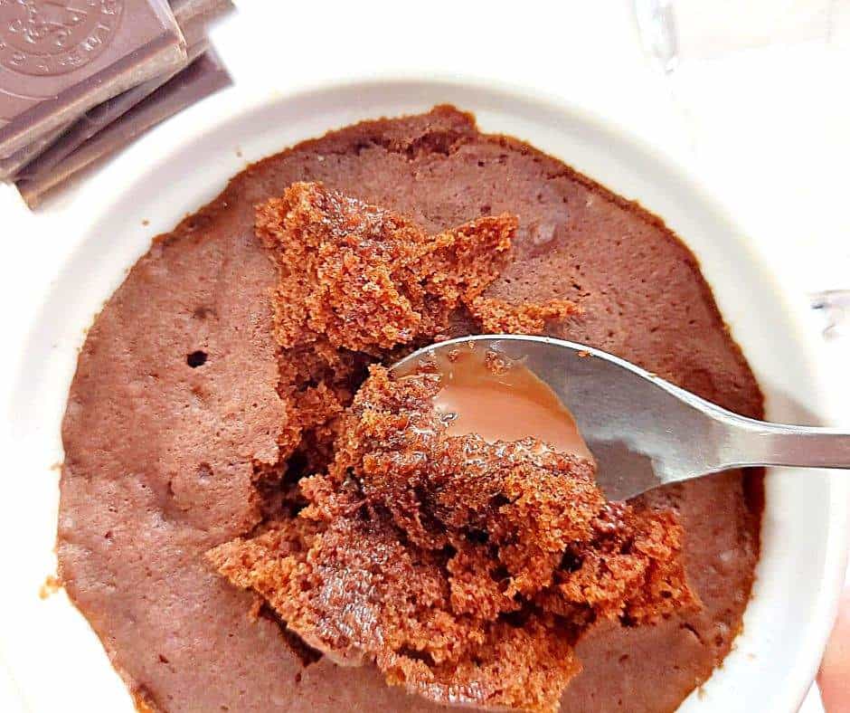 Gooey chocolate mug cake with a stack of chocolate squares on the side