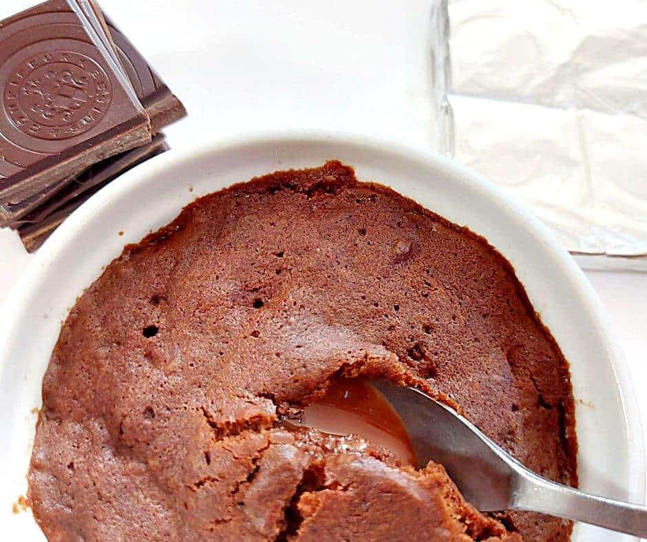 Gooey chocolate mug cake with a stack of chocolate squares on the side and a chocolate bar