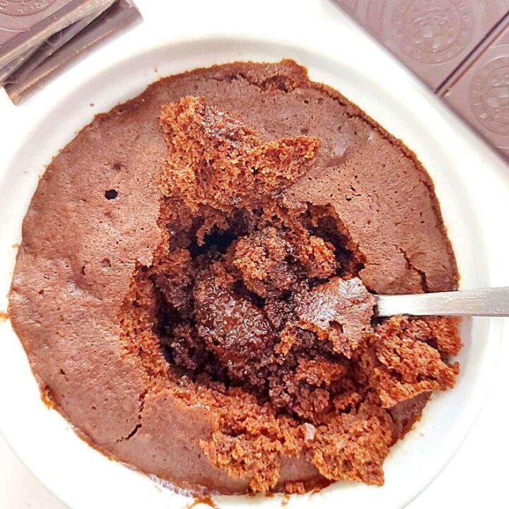 Gooey chocolate mug cake with a stack of chocolate squares and a chocolate bar on the side